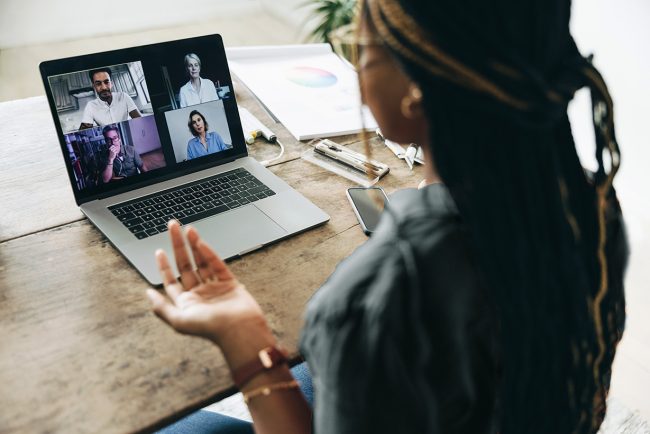 Female down at laptop and engaging in an online meeting with other people. 